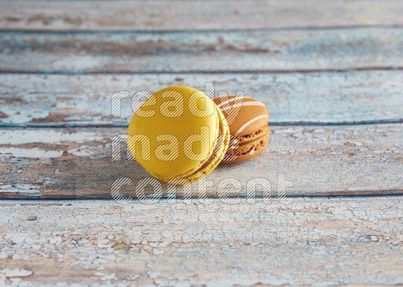 45º Shot of of two assorted Brown Irish Cream, and Yellow Lemon macarons on light blue background
