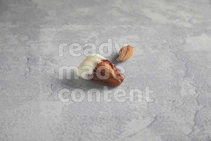 Almond stuffed date coved with white chocolate on a light grey background