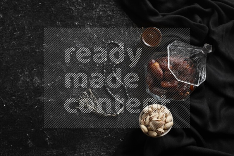 تمر في وعاء زجاجي مع القهوة والمكسرات علي خلفية سوداء خشبية