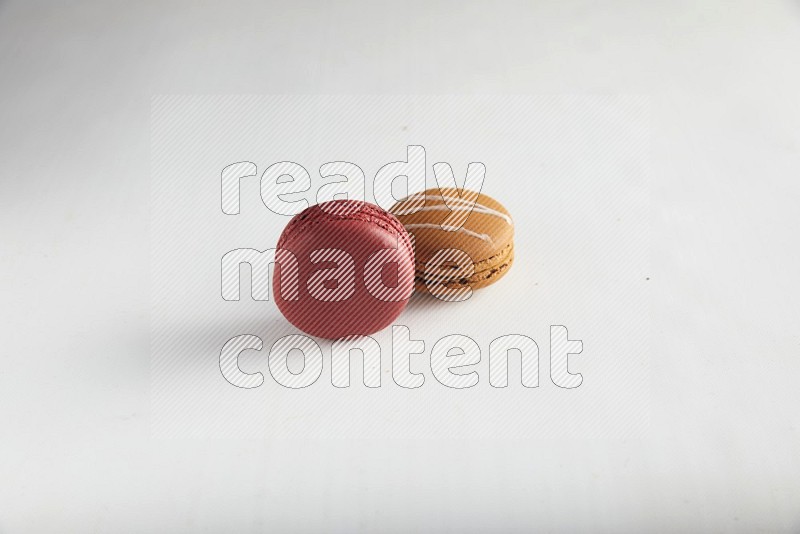 45º Shot of of two assorted Brown Irish Cream, and Red Velvet macarons on white background