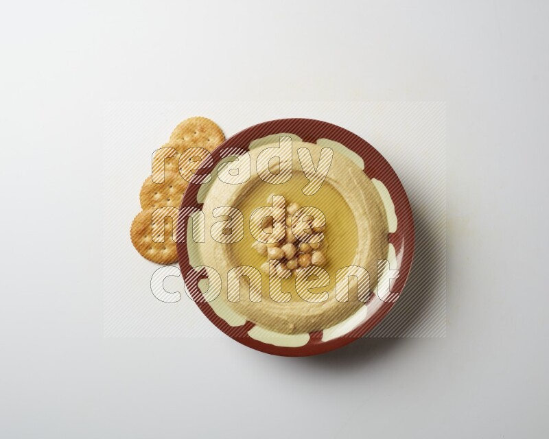 Hummus in a traditional plate garnished with roasted chickpeas  on a white background