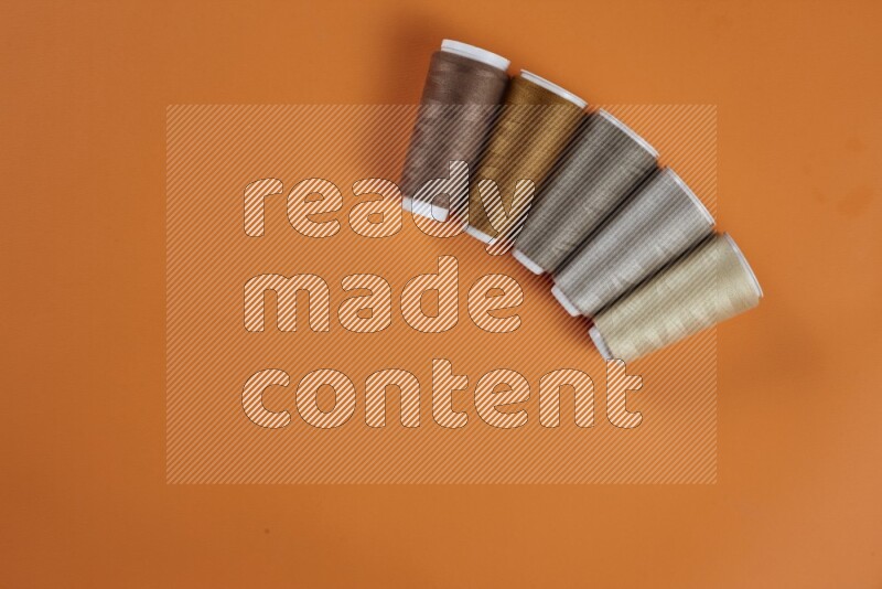 A brown collection of sewing and tailoring tools arranged on a orange background