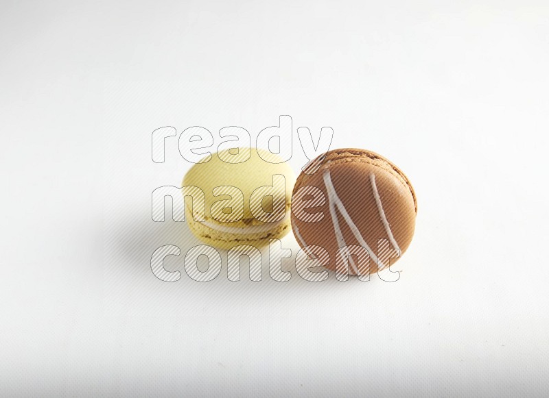 45º Shot of of two assorted Brown Irish Cream, and Yellow Lime macarons on white background