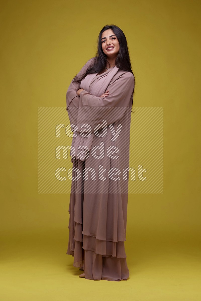 A woman Posing on a Yellow Background wearing Brown Abaya