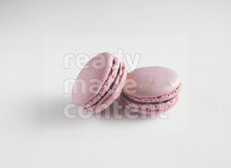45º Shot of two Purple Strawberry macarons on white background