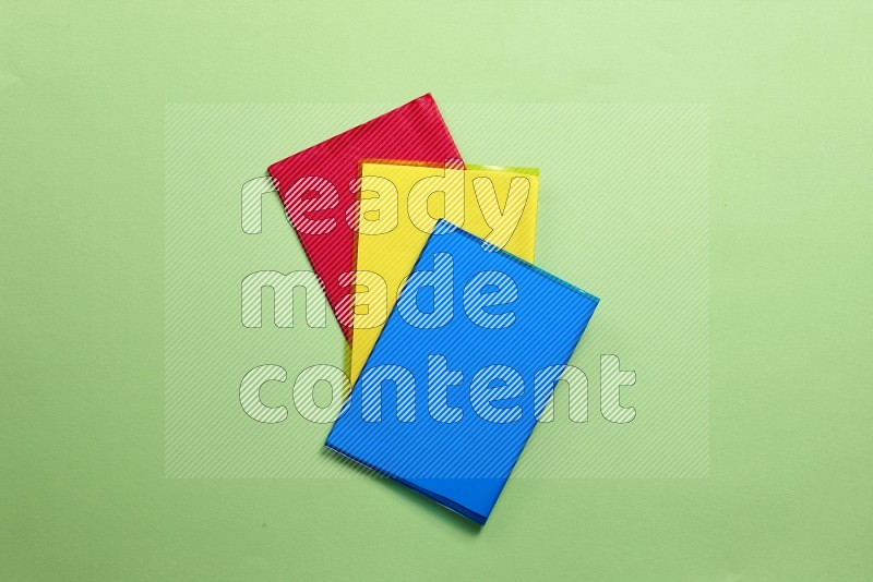 Multicolored notebooks on green background (back to school)