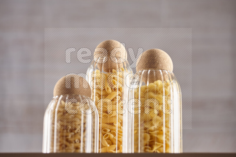 Raw pasta in glass jars on beige background