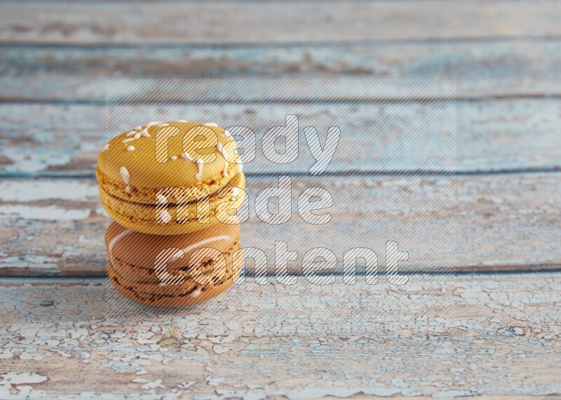 45º Shot of of two assorted Brown Irish Cream, and Yellow Piña Colada macarons on light blue background