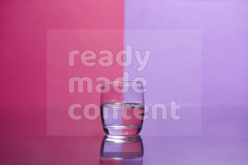 The image features a clear glassware filled with water, set against pink and light purple background