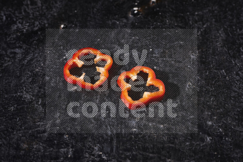 Red bell pepper slices on black background