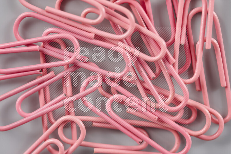 Pink paper clips isolated on a grey background