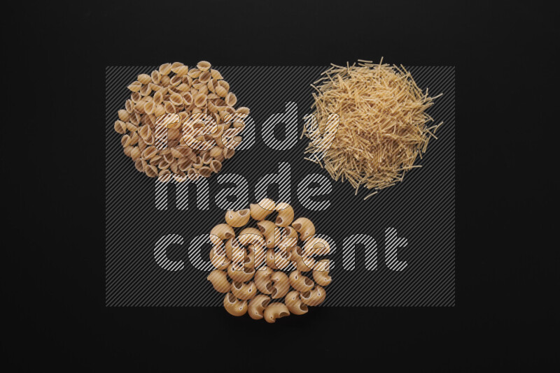 Different pasta types in bunches on black background