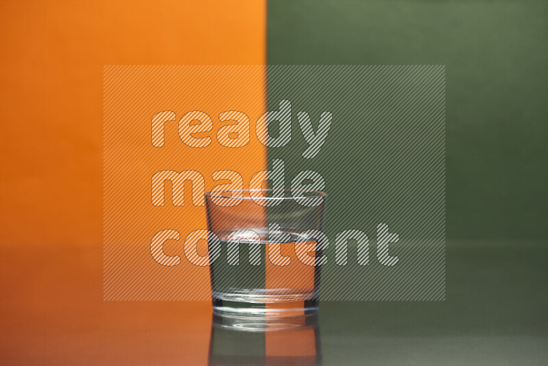تظهر الصورة أواني زجاجية ممتلئة بالماء موضوعة على خلفية من اللونين البرتقالي والأخضر الغامق