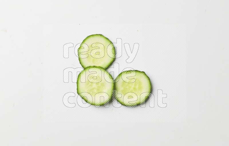 three cucumber slices on white background