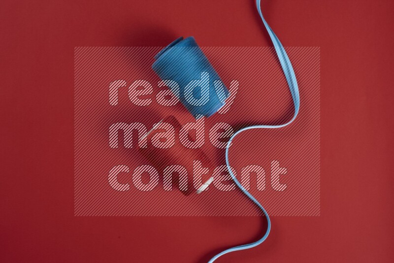 مجموعة من أدوات الخياطة والتفصيل زرقاء وحمراء اللون على خلفية حمراء