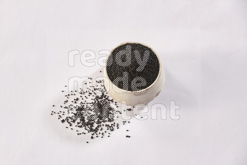 A beige pottery bowl full of black seeds and more seeds spread on a white flooring in different angles