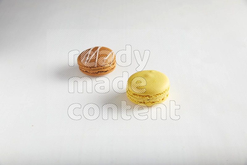 45º Shot of of two assorted Brown Irish Cream, and Yellow Lemon macarons on white background