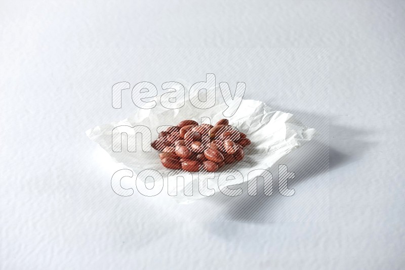 Red skin peanuts on a crumpled piece of paper on a white background in different angles