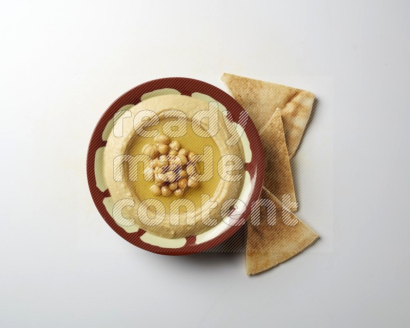 Hummus in a traditional plate garnished with roasted chickpeas  on a white background