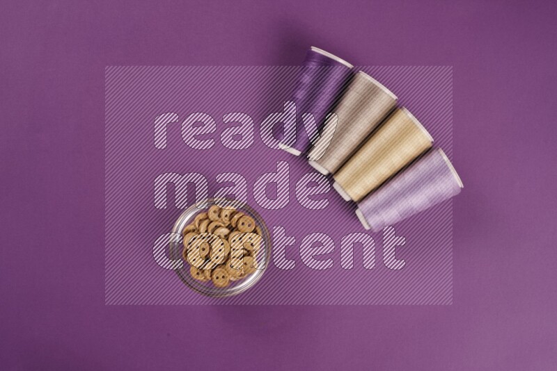 A beige collection of sewing and tailoring tools arranged on a purple background