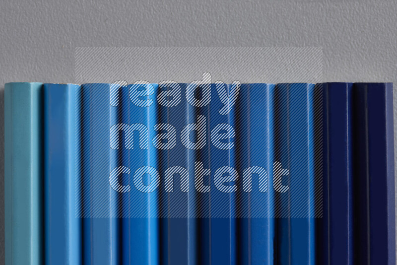 مجموعة من أقلام الرصاص الملونة مرتبة لتعرض تدرجا من الألوان الزرقاء علي خلفية رمادية