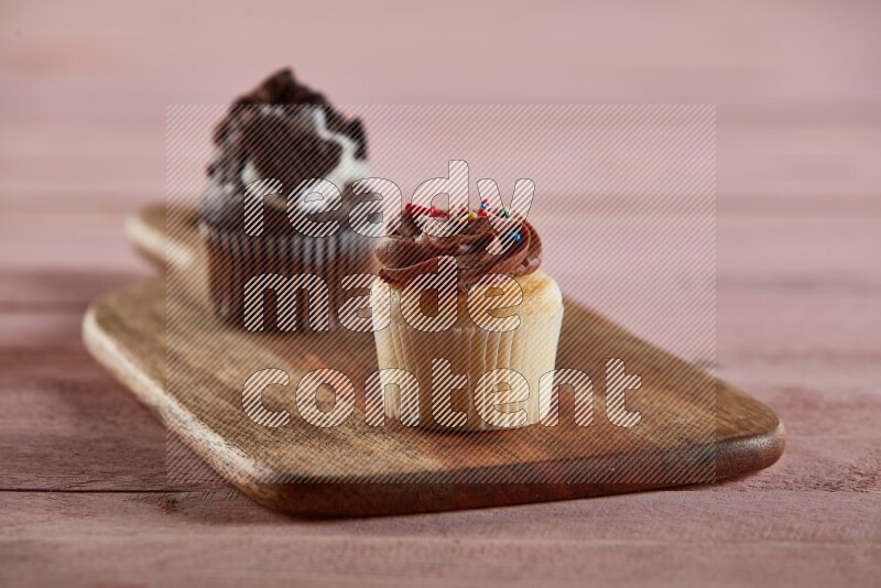 Vanilla mini cupcake topped with chocolate cream on a wooden board