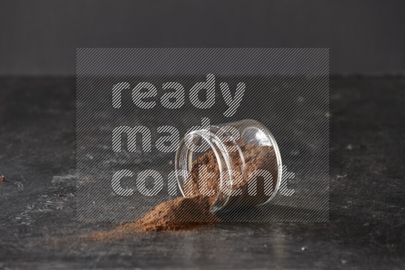 وعاء زجاجي مقلوب ممتلئ ببودرة القرنفل على أرضية سوداء