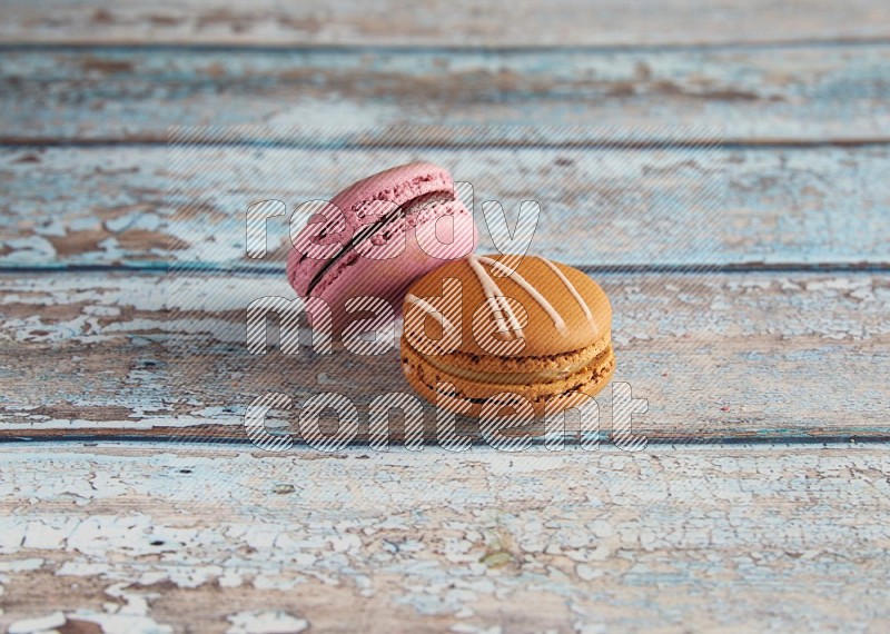 45º Shot of of two assorted Brown Irish Cream, and Purple Strawberry macarons  on light blue background