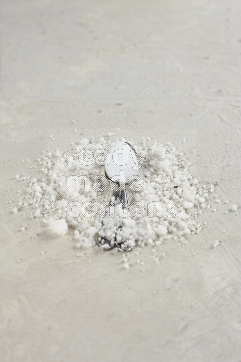 2 metal spoons filled with fine table salt and fine pink himalayan salt on white background