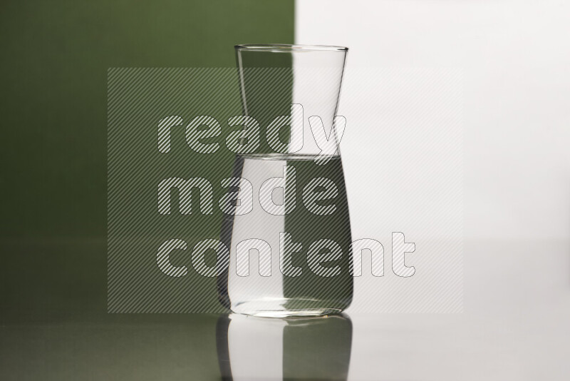 The image features a clear glassware filled with water, set against white and dark green background