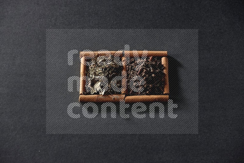 2 squares of cinnamon sticks full of cloves and dried basil on black flooring