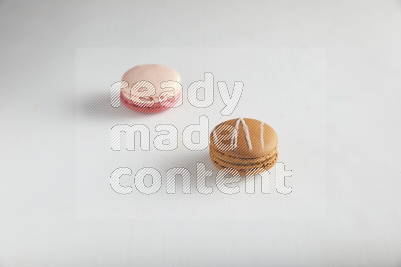 45º Shot of of two assorted Brown Irish Cream, and Pink Litchi Raspberry macarons on white background