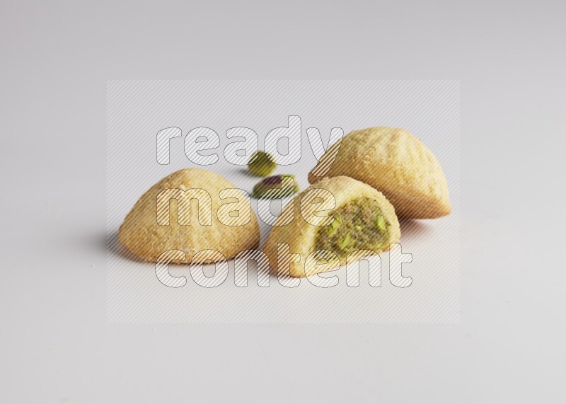 Three Pieces of Maamoul filled with pistachio paste  one of them is cut direct on white background