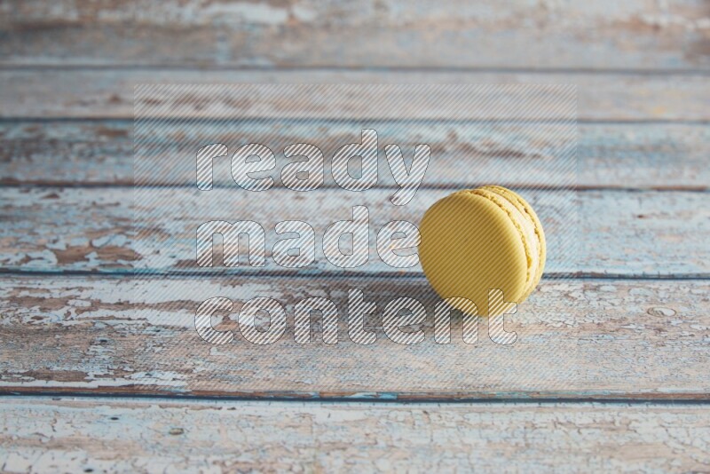 45º Shot of Yellow Lime macaron on light blue wooden background