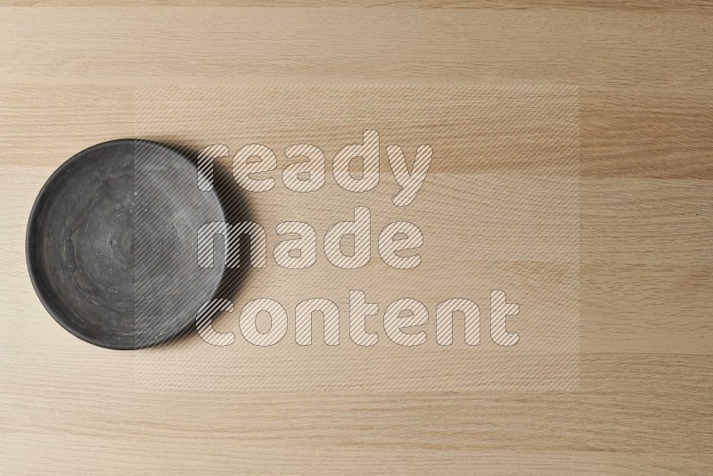 Top View Shot Of A Black Pottery Circular Plate on Oak Wooden Flooring
