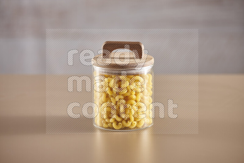 Raw pasta in glass jars on beige background