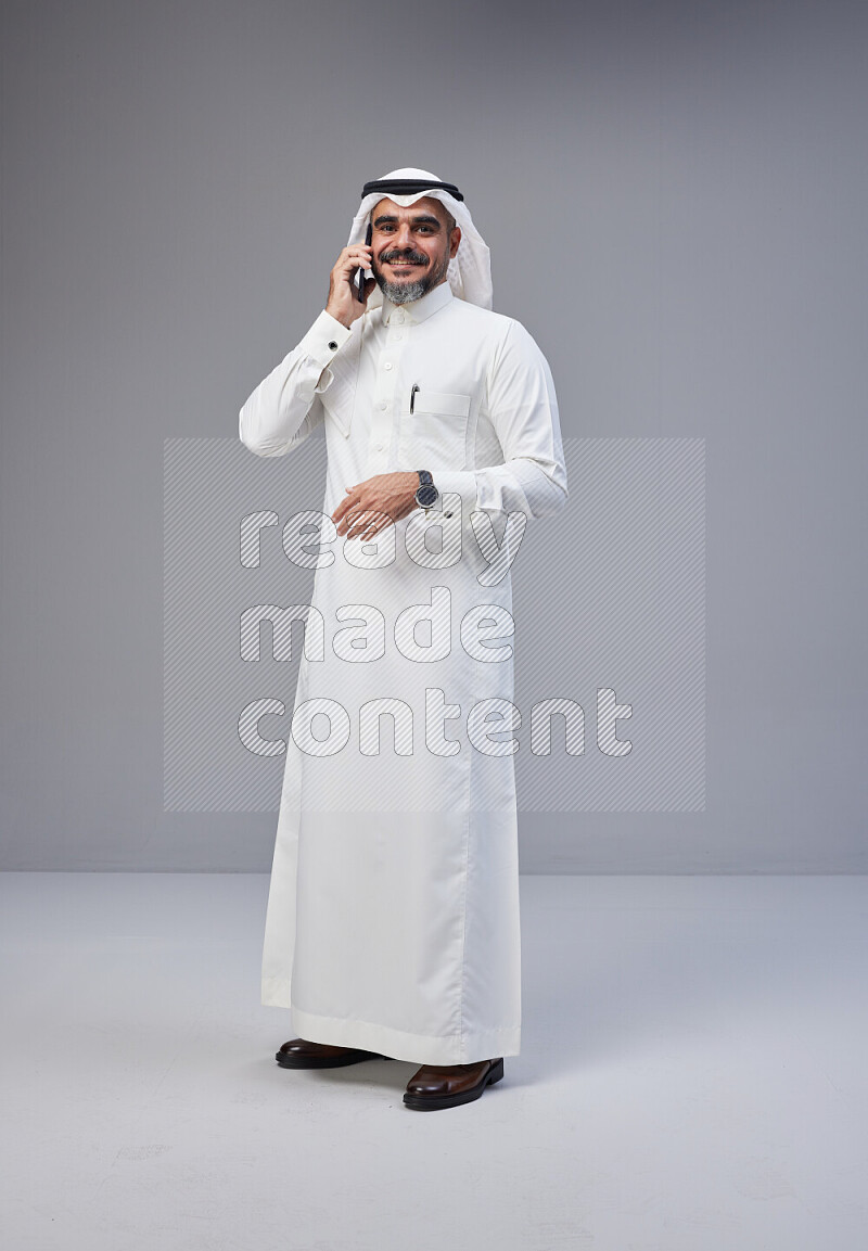 رجل سعودي يرتدي ثوب وشماغ ابيض يتحدث بهاتفه الجوال
