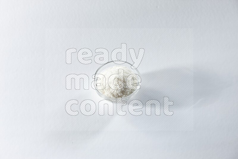 A glass bowl full of desiccated coconut on a white background in different angles