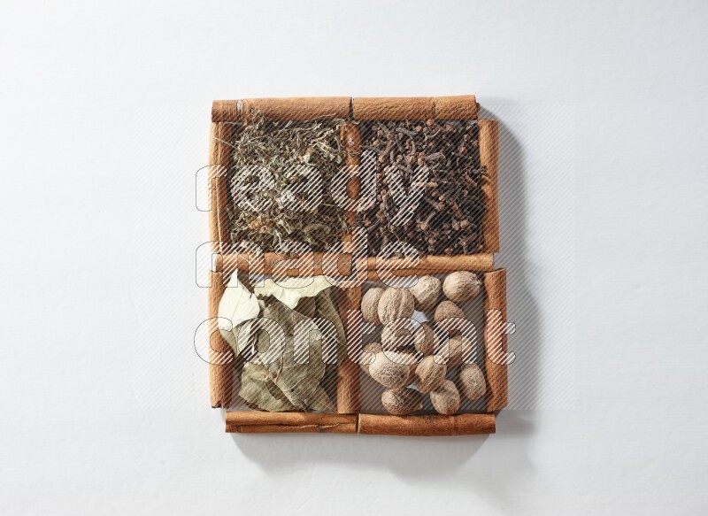 4 squares of cinnamon sticks full of bay laurel leaves, dried basil, cloves and nutmegs on white flooring