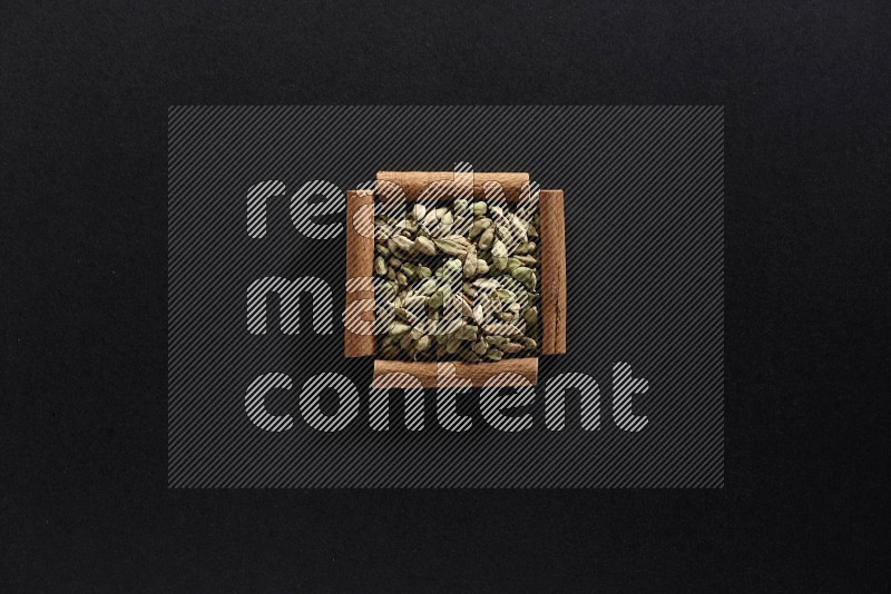 A single square of cinnamon sticks full of Cardamom on black flooring