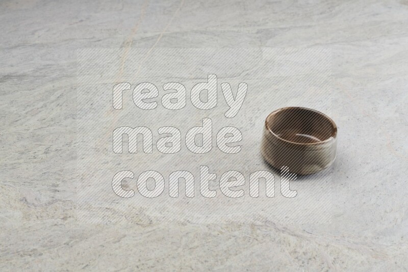 A brown pottery bowl on grey marble background