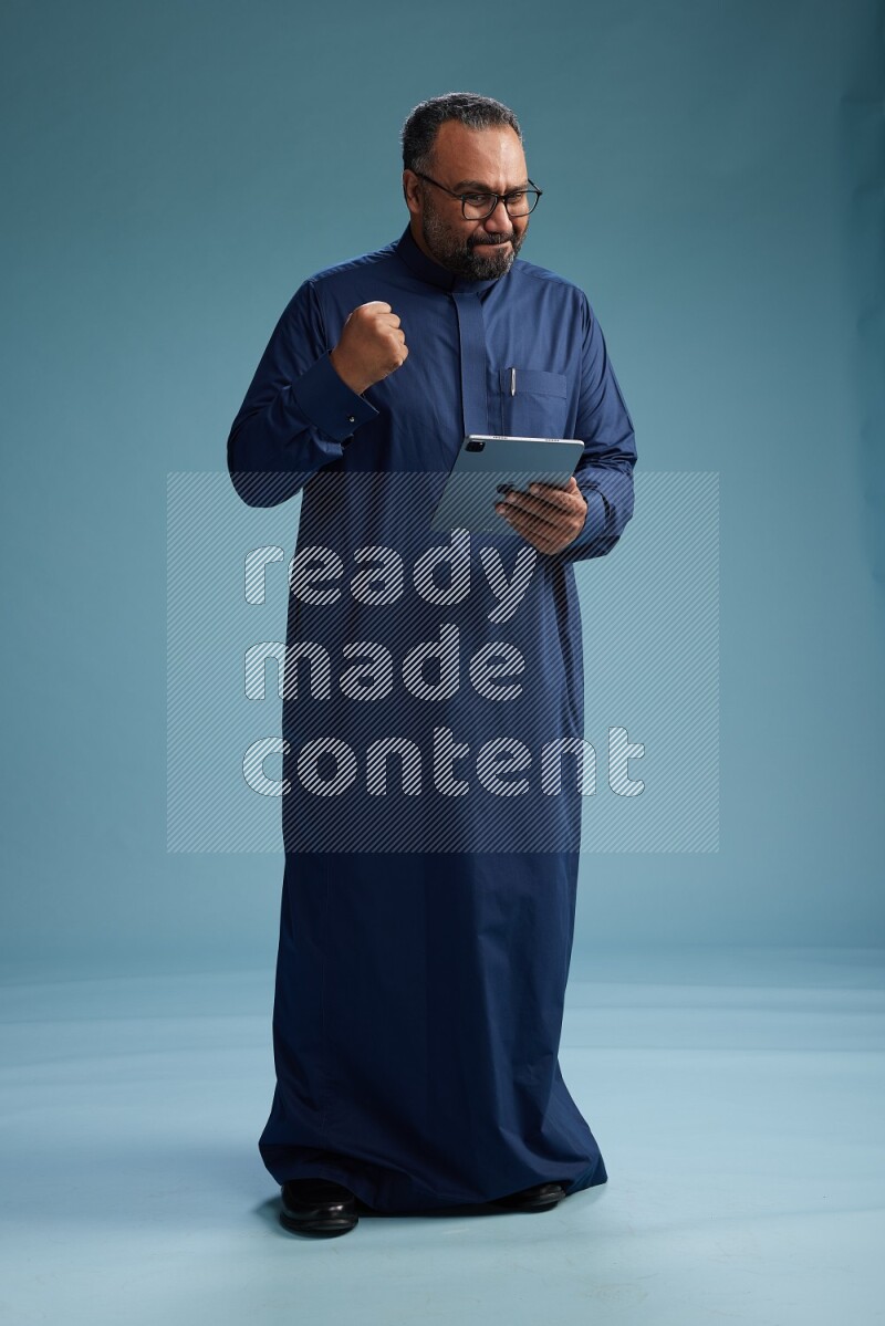 Saudi Man without shimag Standing working on tablet on blue background