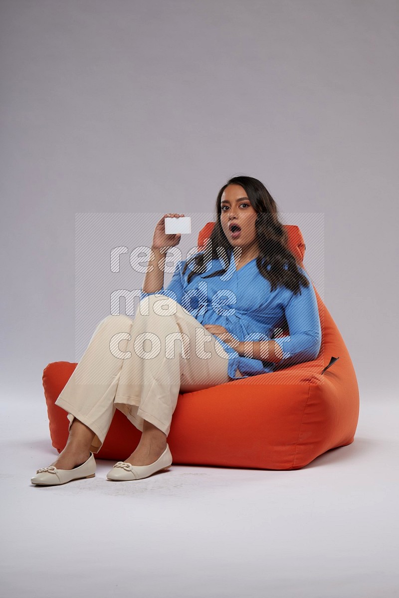 A woman sitting on an orange beanbag and holding ATM card