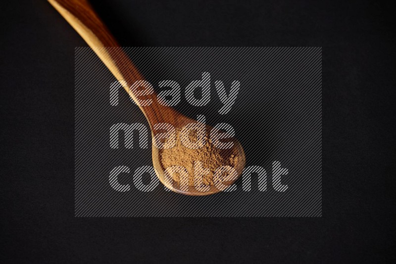 Cinnamon powder in a wooden ladle spoon on black background in different angles