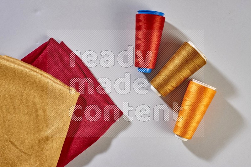 Multicolored fabrics with sewing supplies on grey background