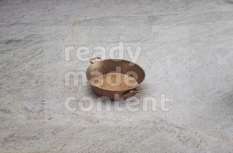 A Small Copper Pan On Grey Marble Flooring