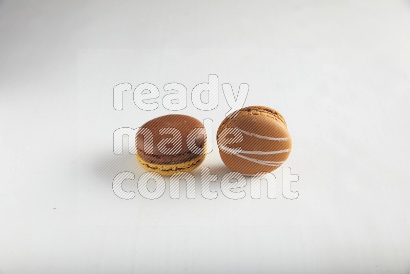 45º Shot of of two assorted Brown Irish Cream, and Yellow, and Brown Chai Latte macarons on white background