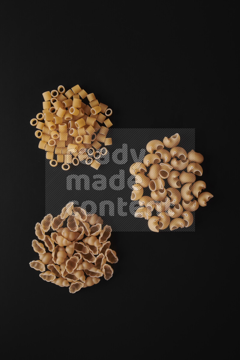 Different pasta types in bunches on black background