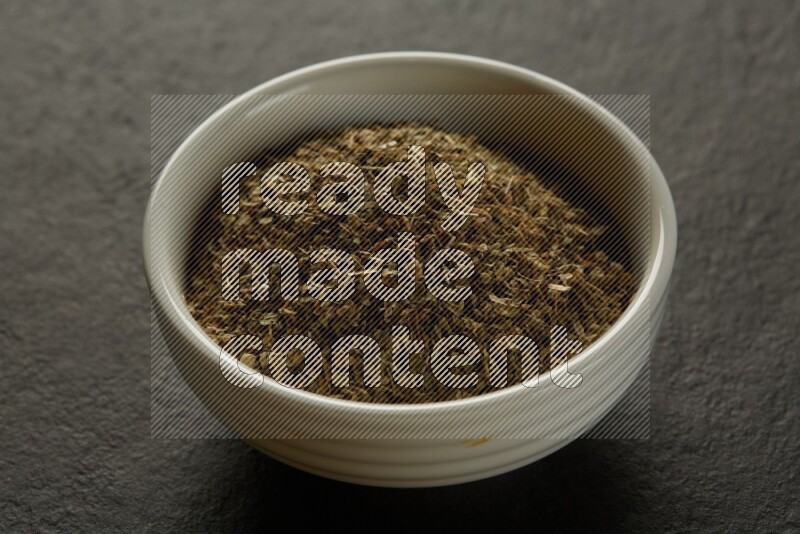 white ceramic round sauce bowl filled with herbs on grey textured countertop