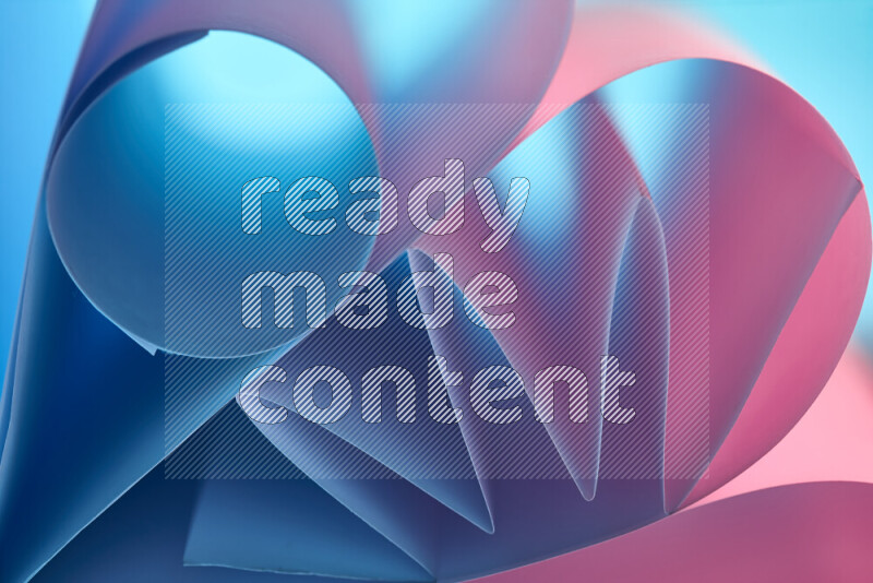 An artistic display of paper folds creating a harmonious blend of geometric shapes, highlighted by soft lighting in blue and pink tones